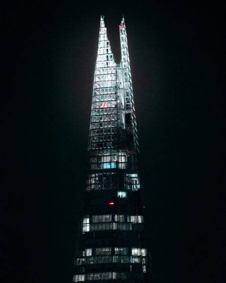 Hoog glanzend gebouw met twee spitse toppen, verlicht in het donker.