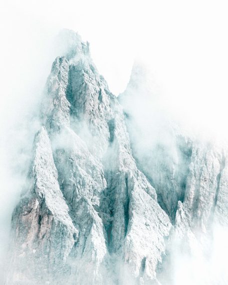 Bergtoppen bedekt met sneeuw en omgeven door mist.